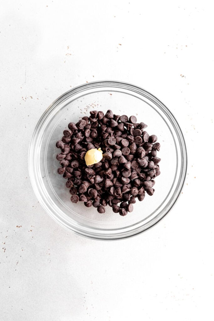Glass bowl of chocolate chips and a scoop of butter.