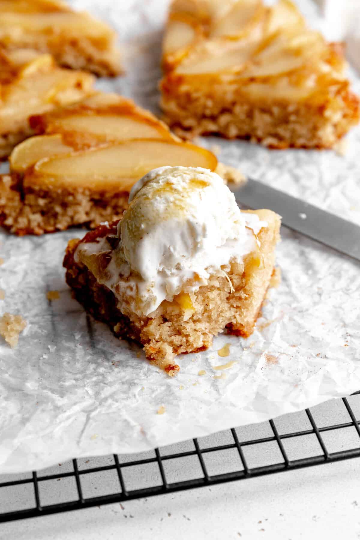 Slice of pear upside down cake topped with a scoop of ice cream.