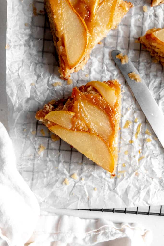 Slice of pear upside down cake on a sheet of white parchment paper.