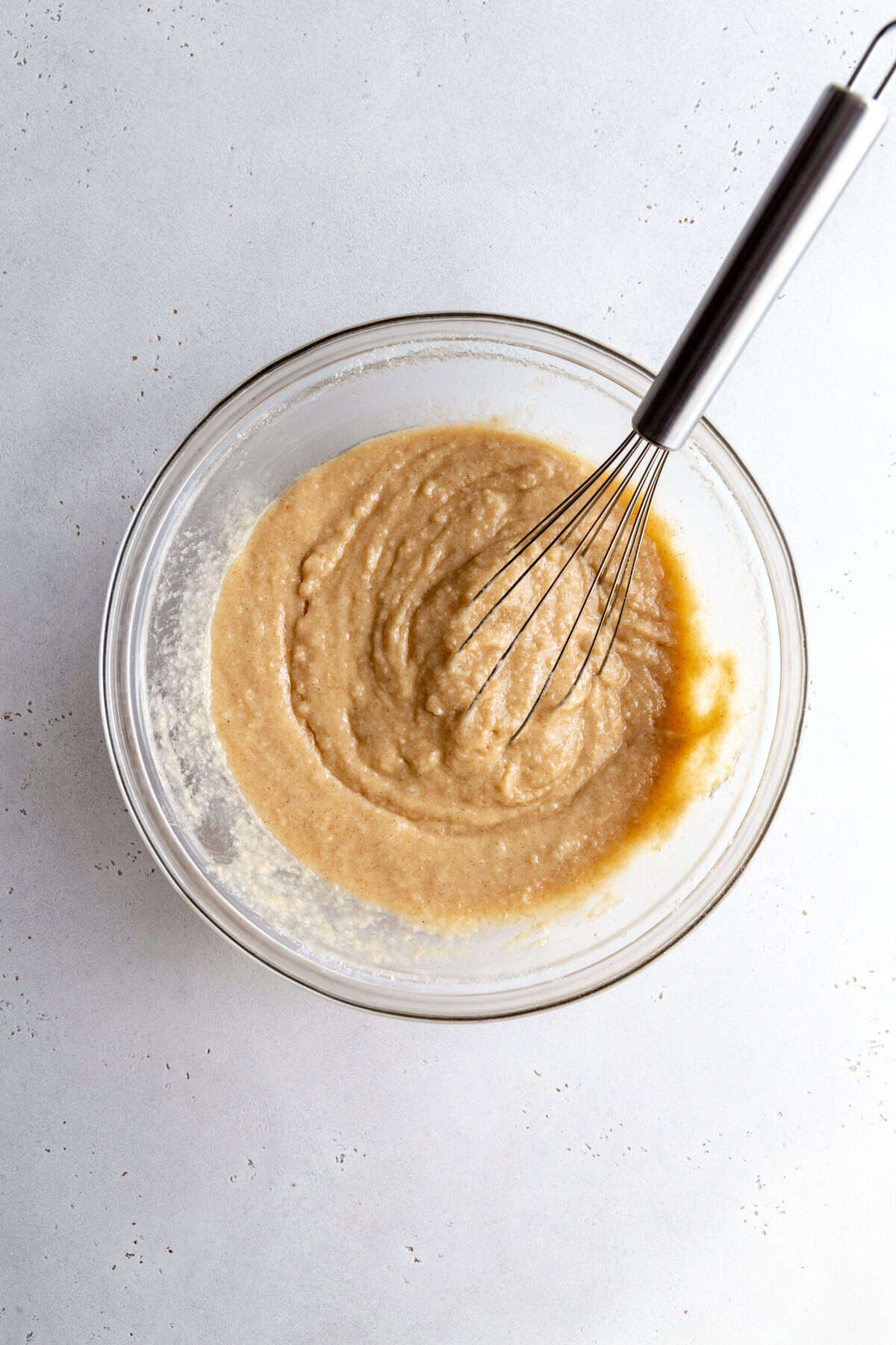 Almond cake batter in a bowl with a whisk.