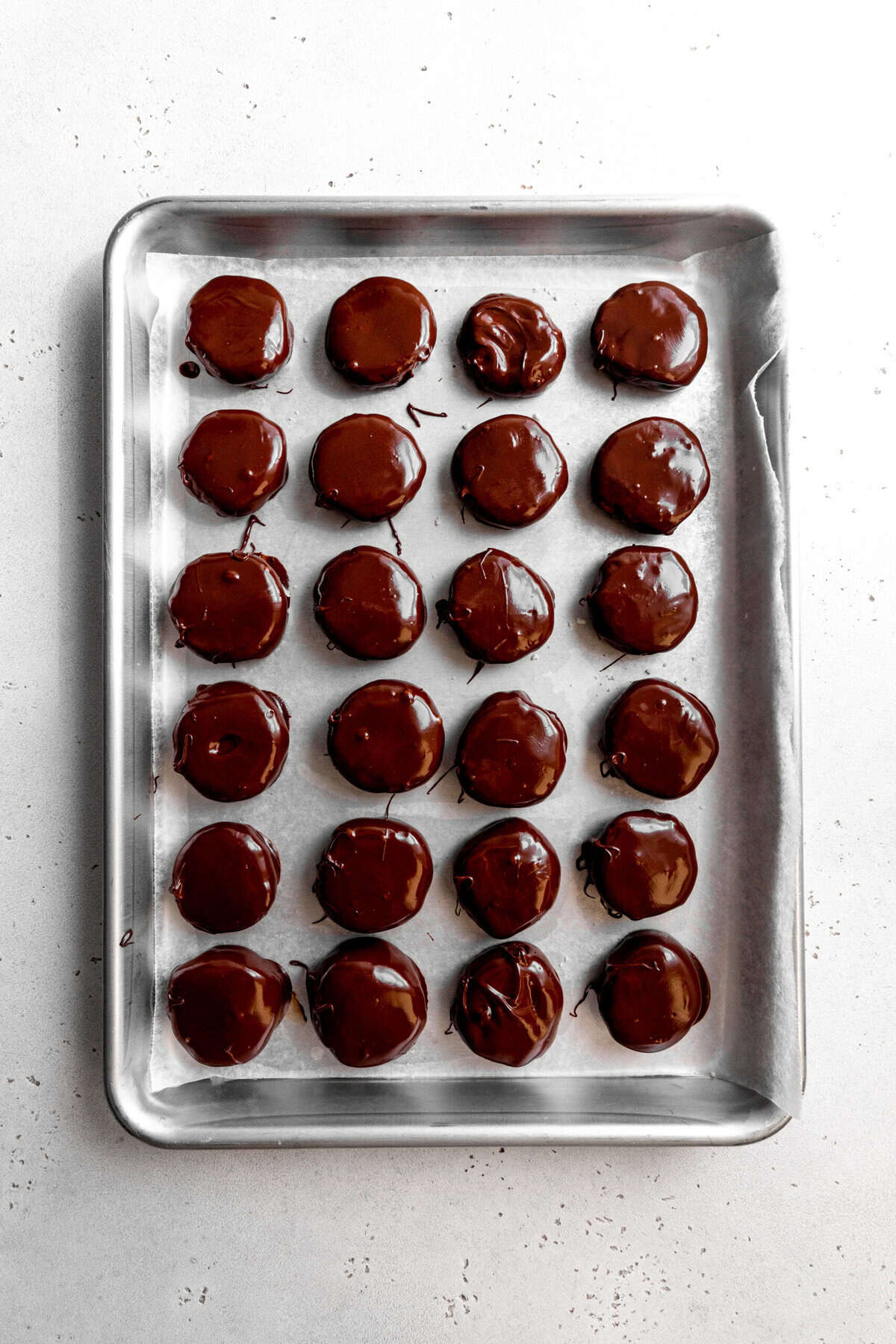 Coated, unset peppermint patties on a baking sheet.