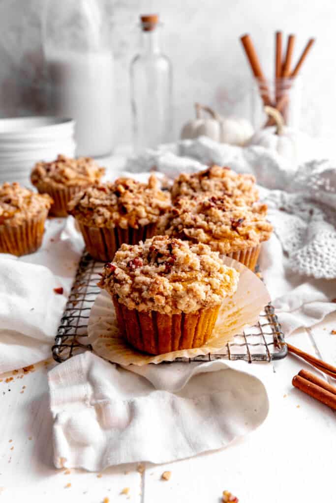 Paper wrapper peeling off a pumpkin muffin with streusel topping.