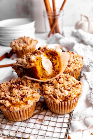 Pumpkin muffin with cream cheese filling with a bite taken out of it on a wire rack.