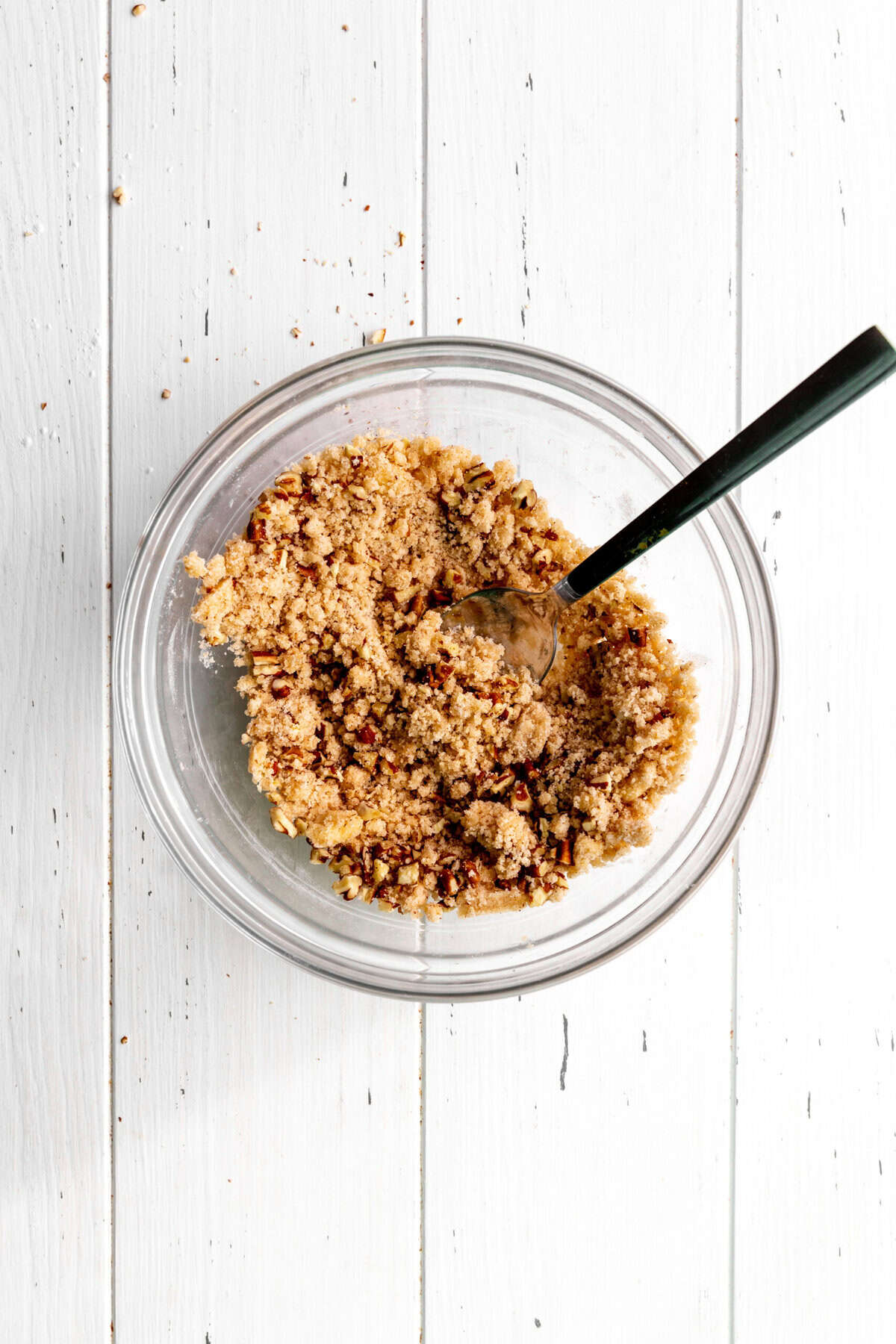 Glass bowl of pecan streusel topping with a spoon.