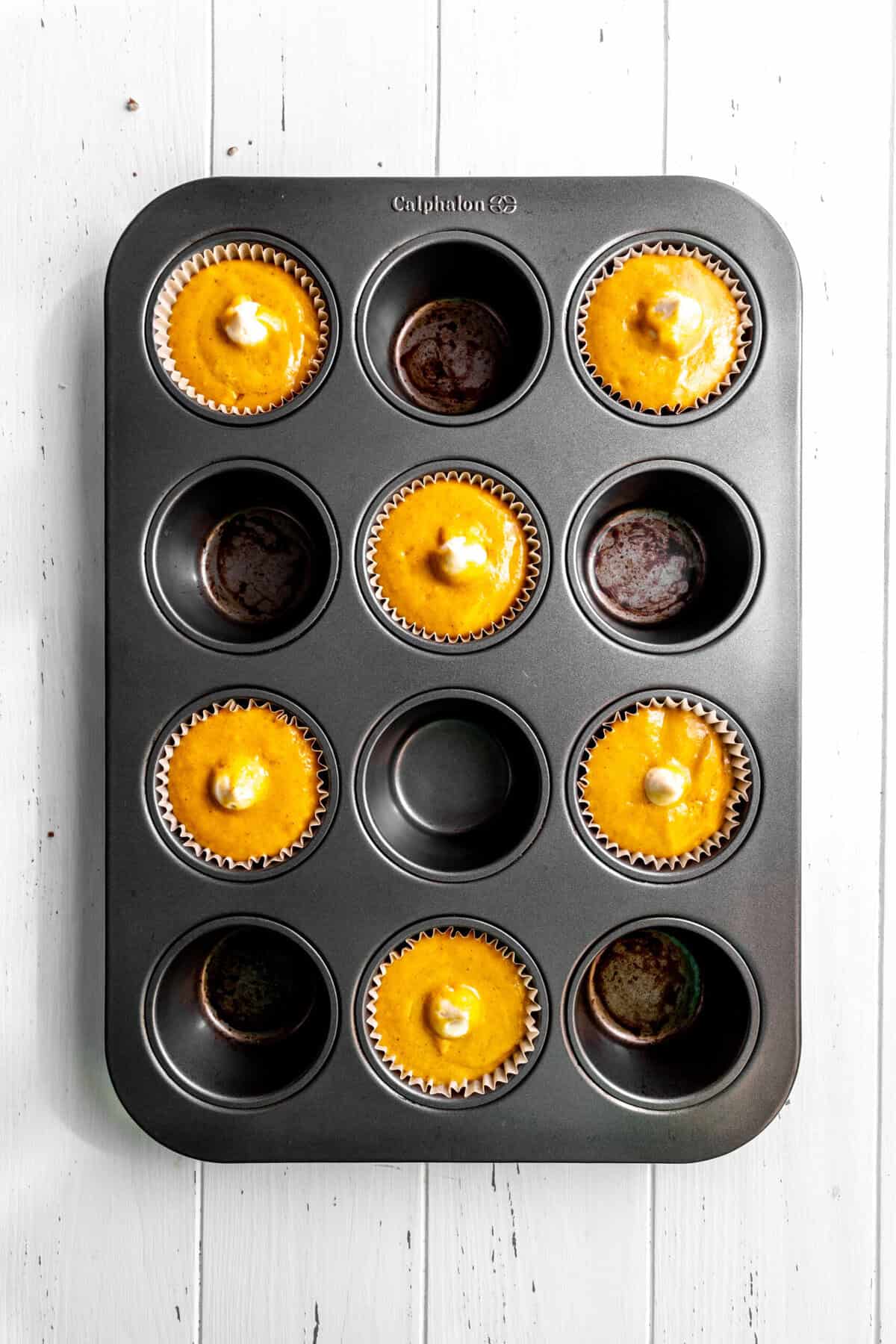 Unbaked pumpkin muffins filled with cream cheese.