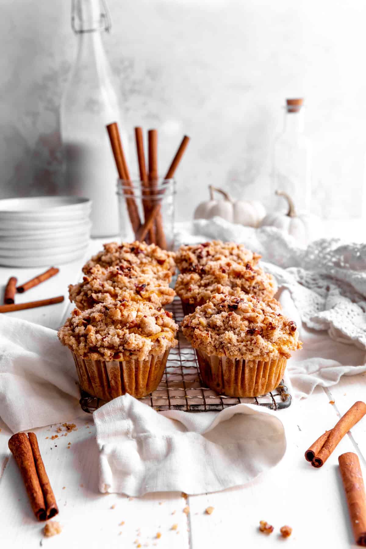 Pumpkin muffins on a wire rack, a jug of milk and a stack of white plates.