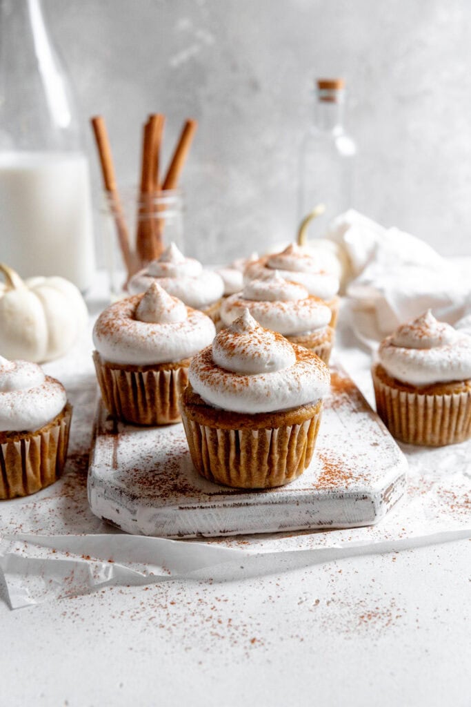 Pumpkin pie cupcakes, a jug of milk and cinnamon sticks.