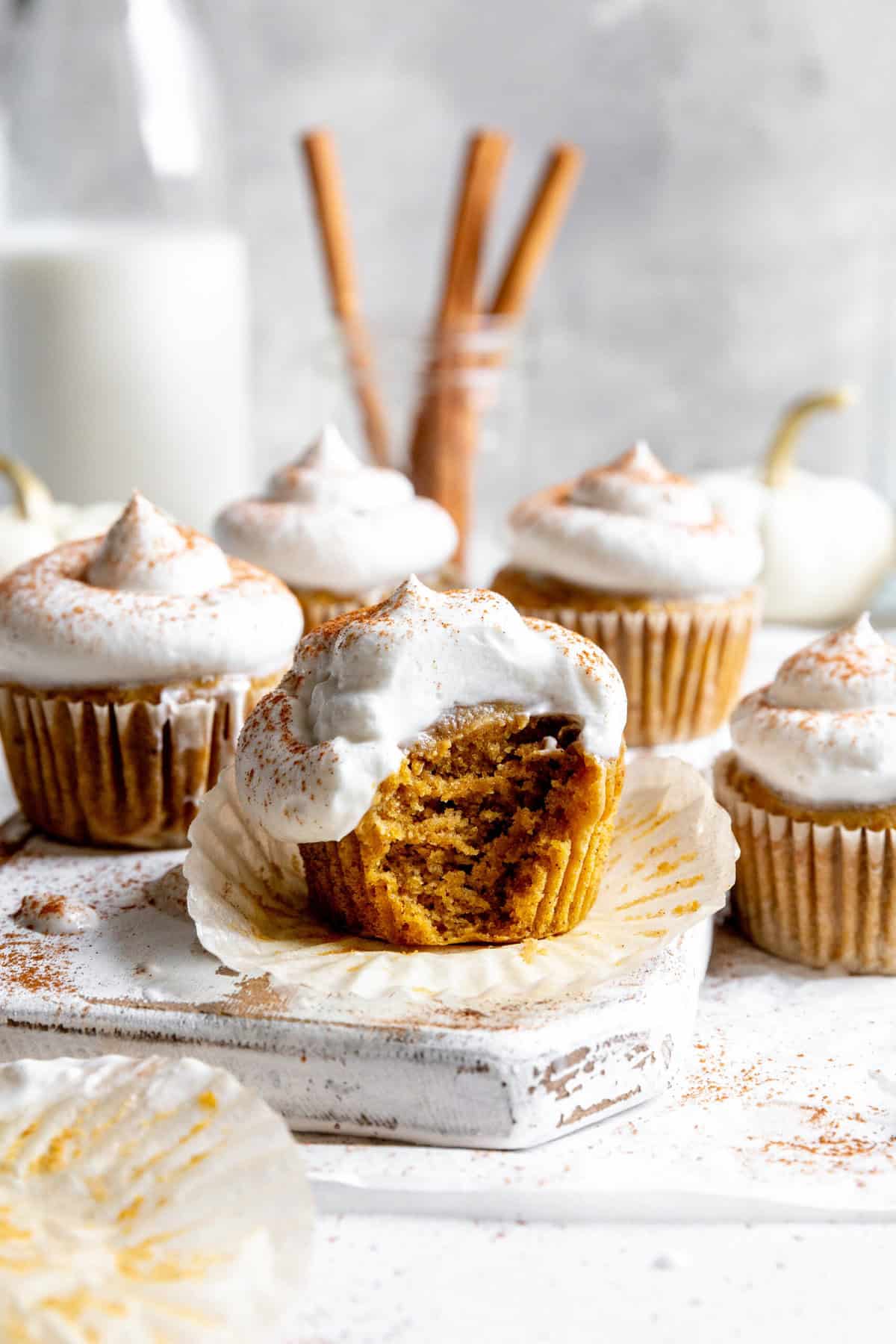 Pumpkin pie cupcake with a bite taken out of it and a jug of milk.