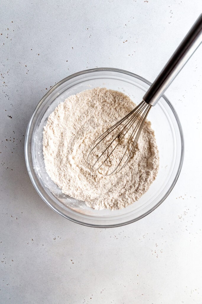 Flour in a glass bowl with a whisk.