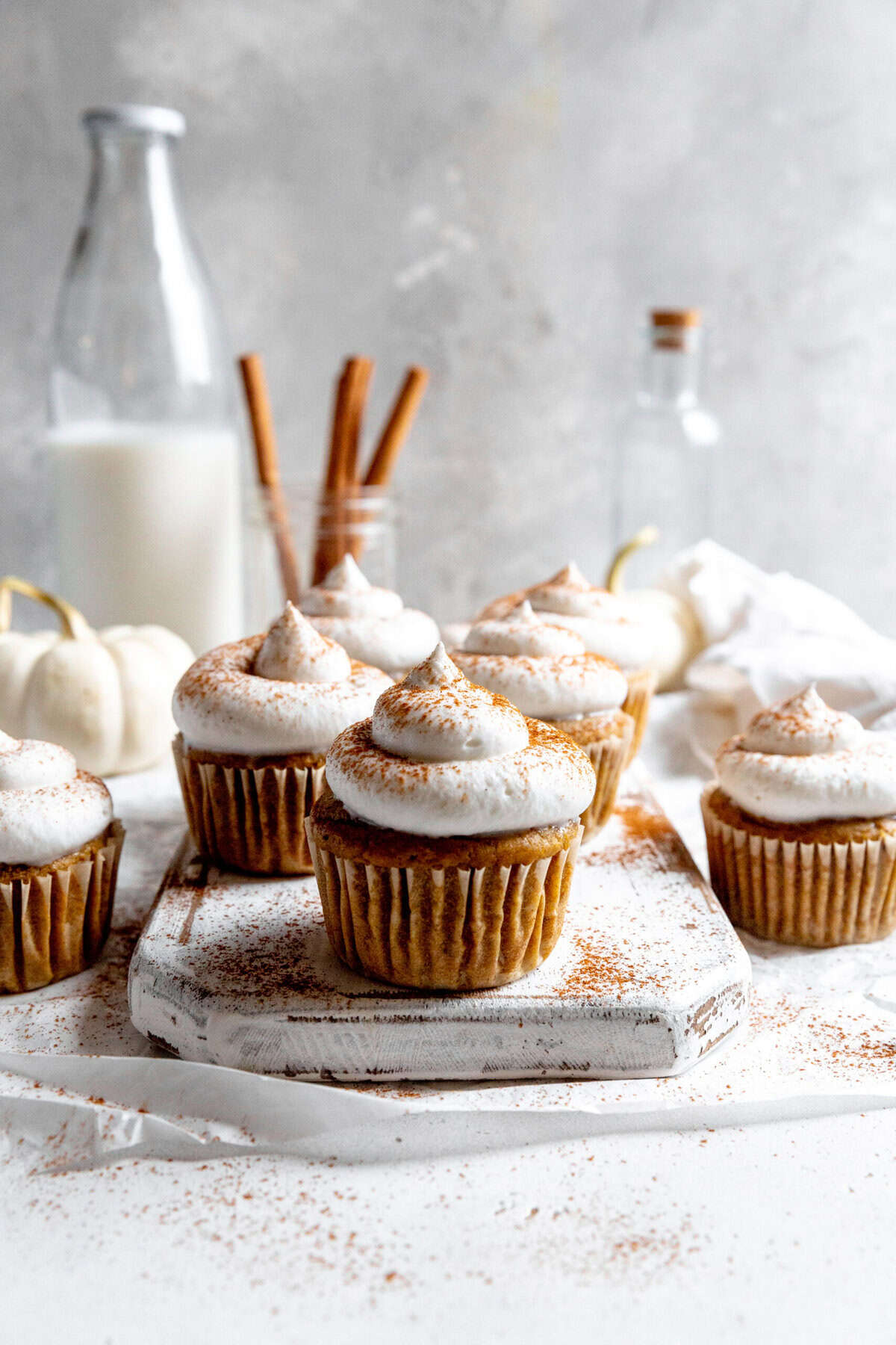 Pumpkin cupcakes topped with whipped cream and a sprinkle of cinnamon.