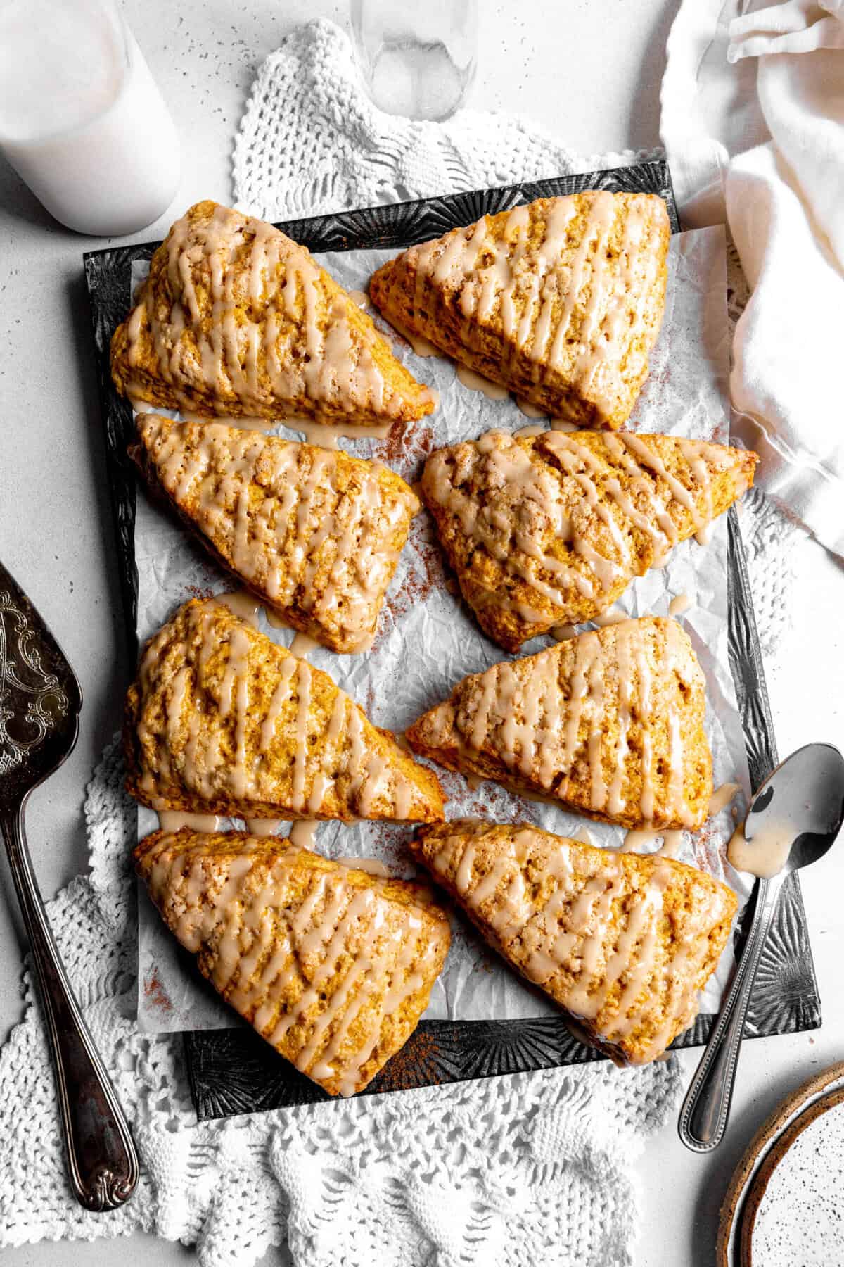 Pumpkin scones drizzled in maple glaze, a jug of milk and a linen napkin.