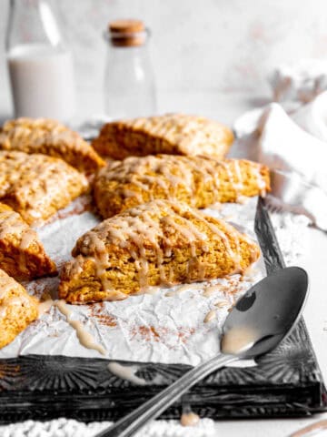 Pumpkin scone, a spoon covered in maple glaze and a linen napkin.