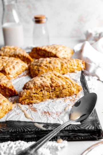 Pumpkin scone, a spoon covered in maple glaze and a linen napkin.