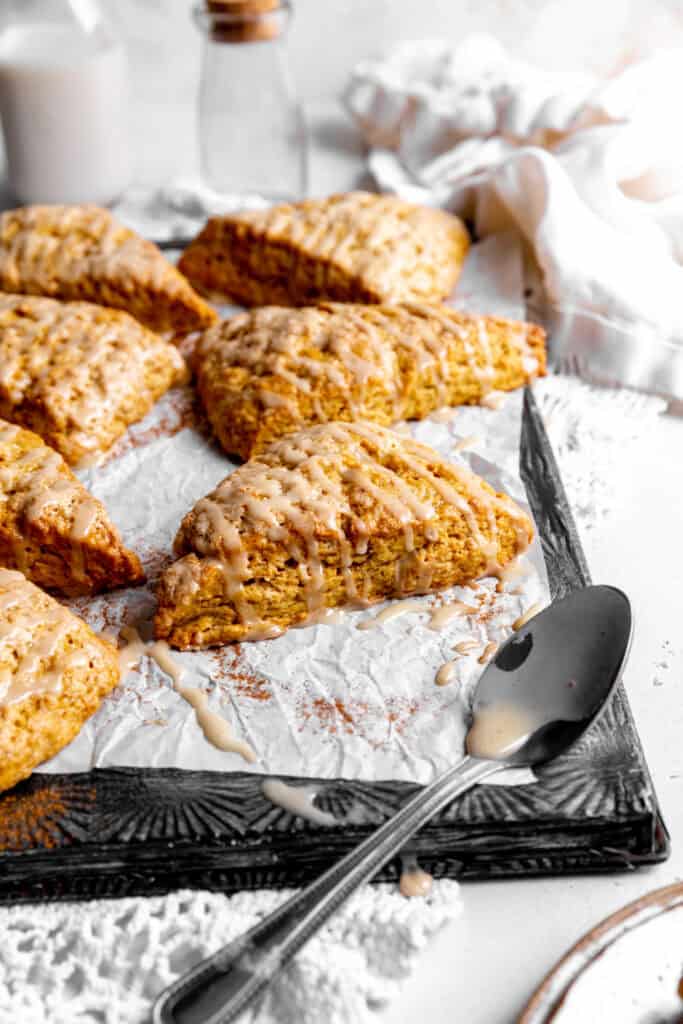 Pumpkin scone, a spoon covered in maple glaze and a linen napkin.