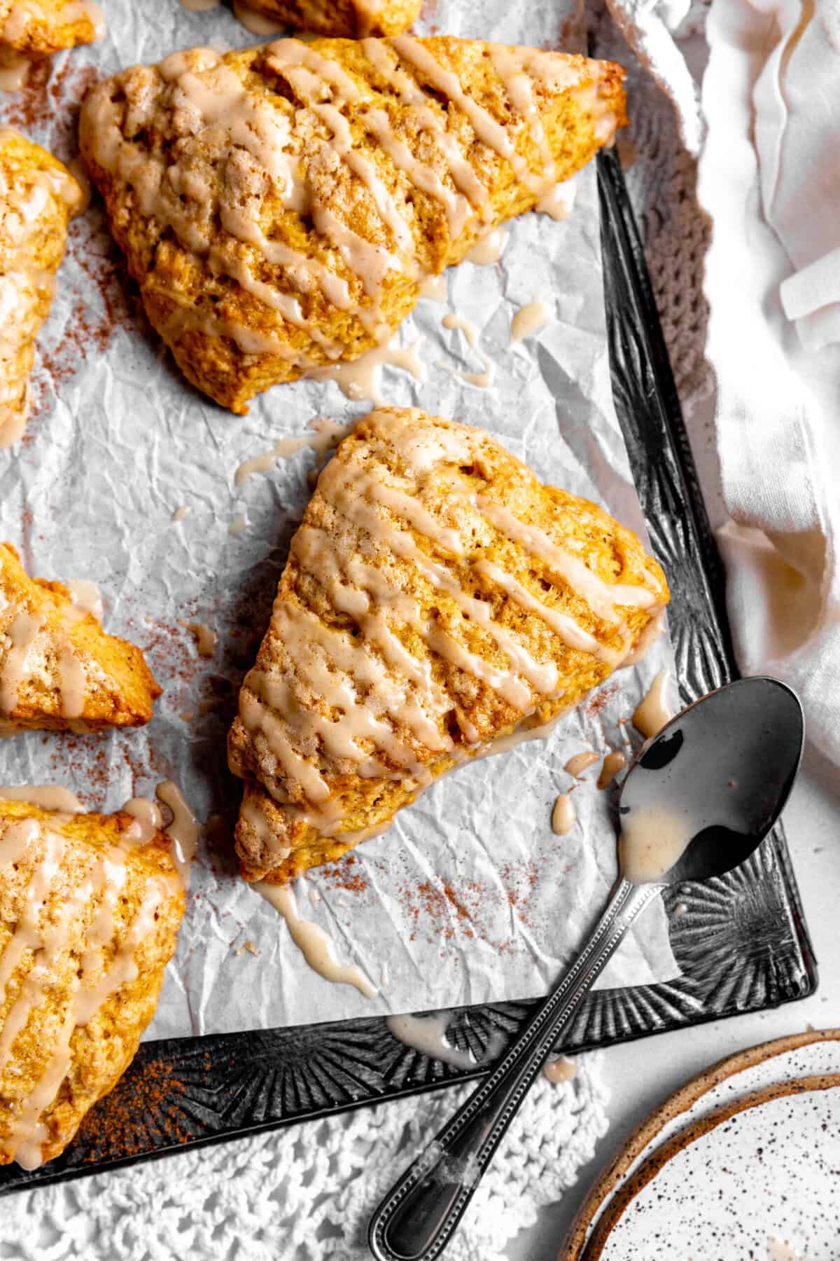 Pumpkin scones, a spoon and a stack of white plates.