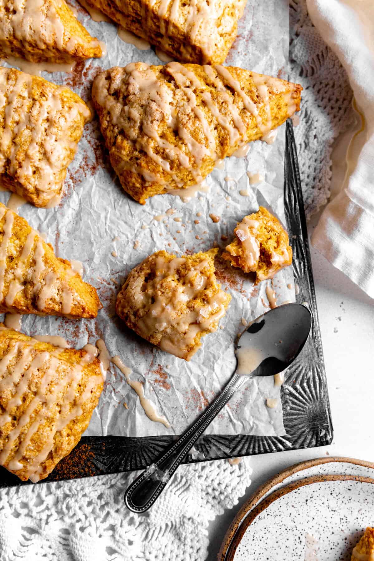 Pumpkin scone broken in half on a baking sheet.