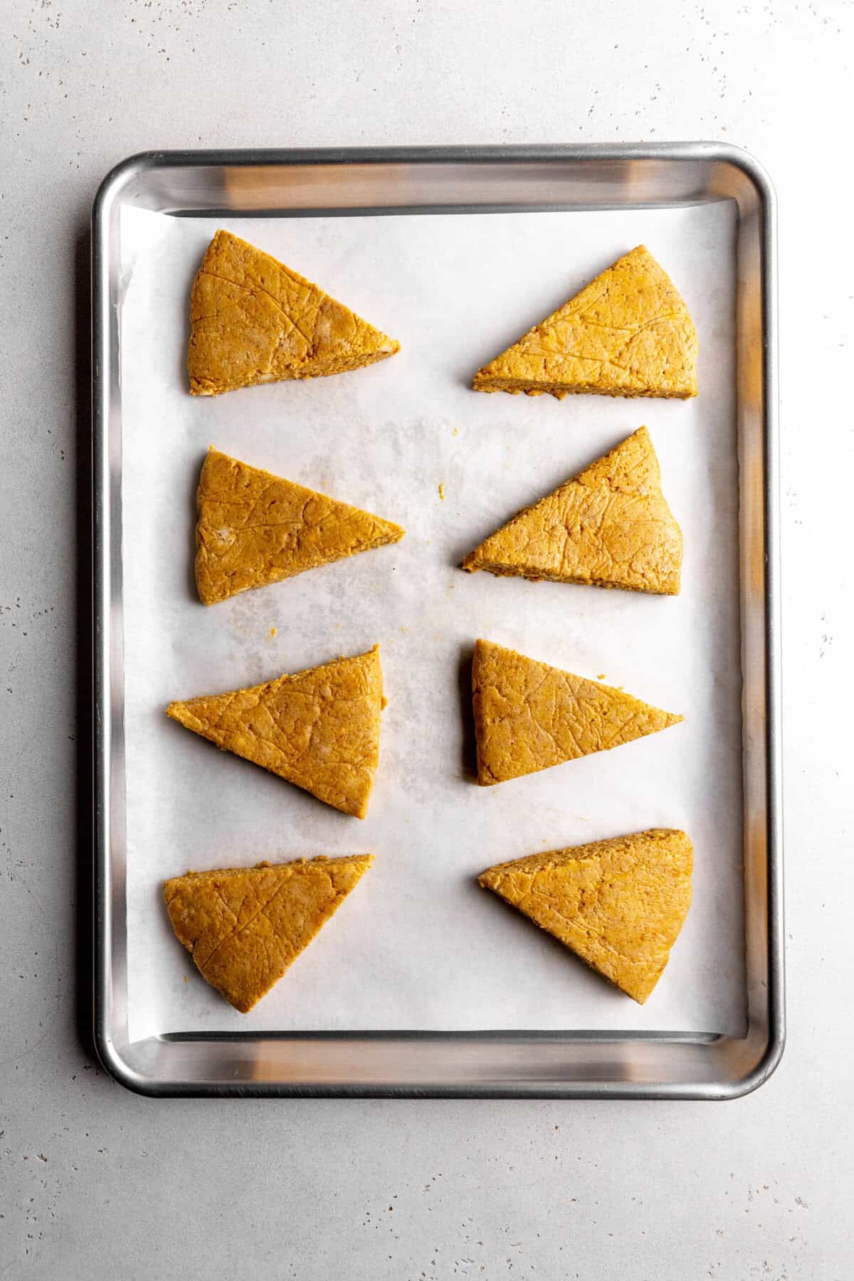 Unbaked pumpkin scones on a baking sheet.