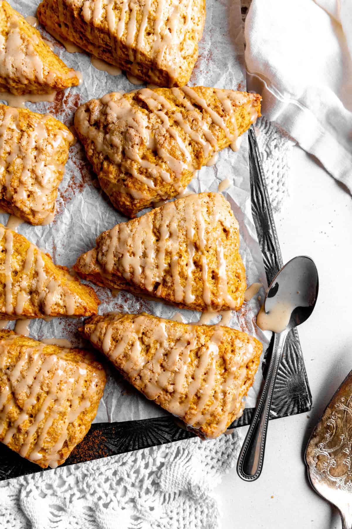 Pumpkin scones drizzled with maple glaze on a baking sheet.