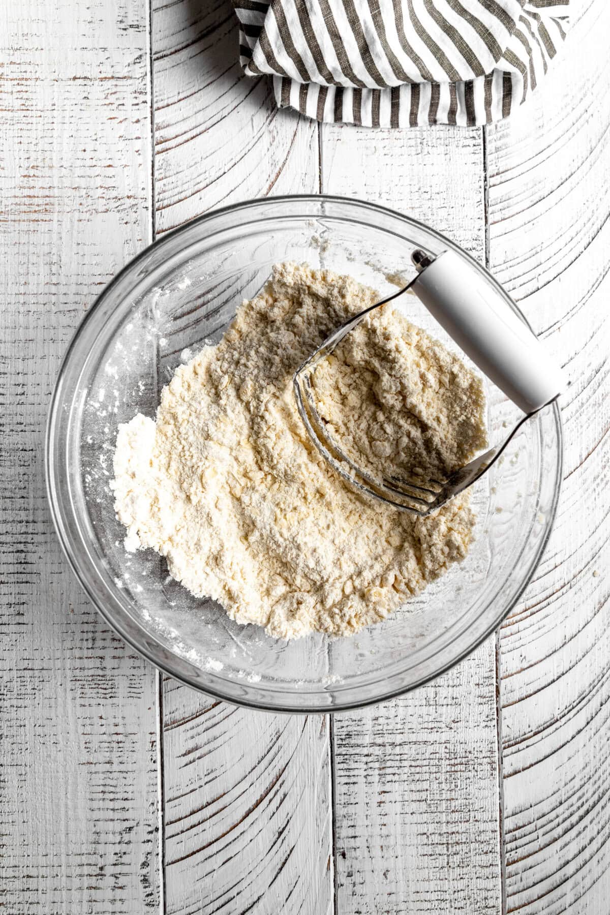 Pastry cutter in a glass bowl of flour.