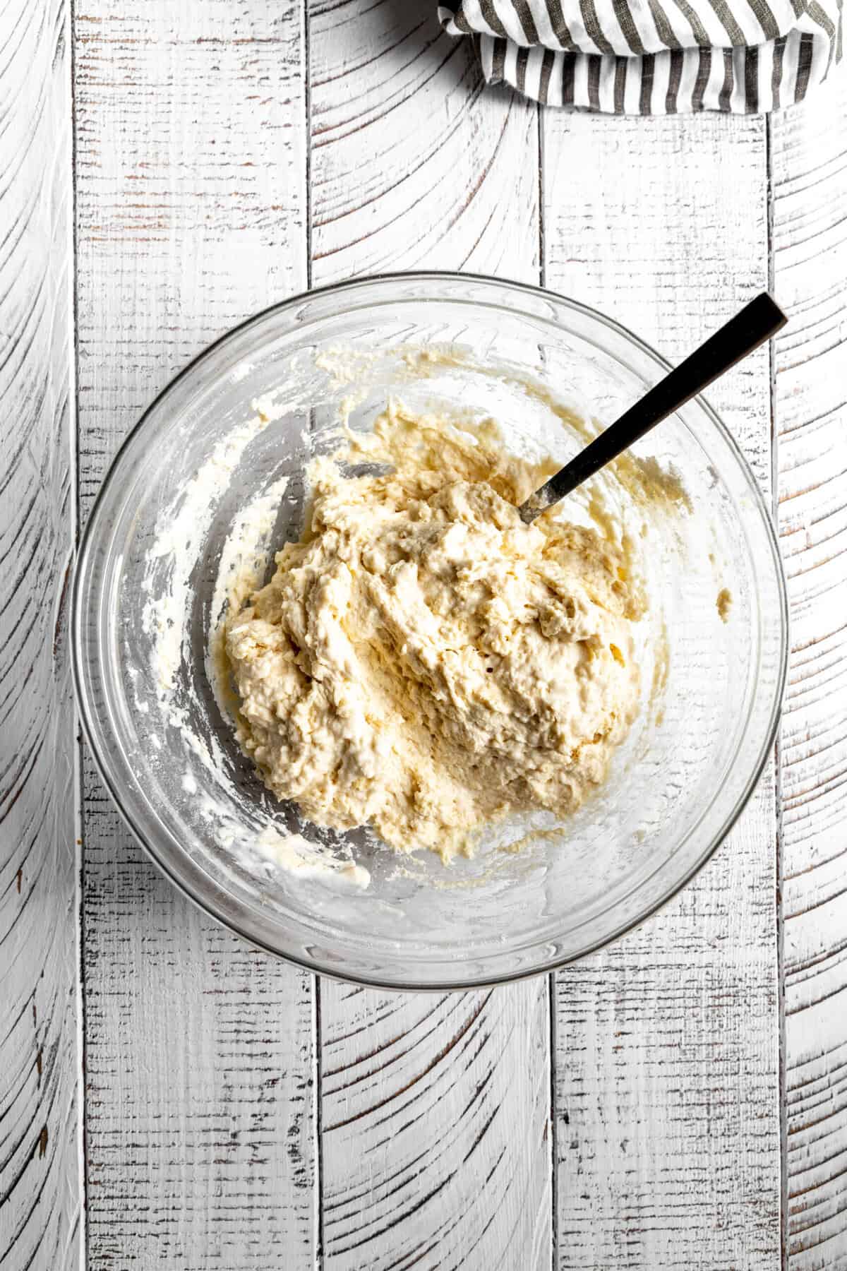 Glass bowl of biscuit dough with a spoon.