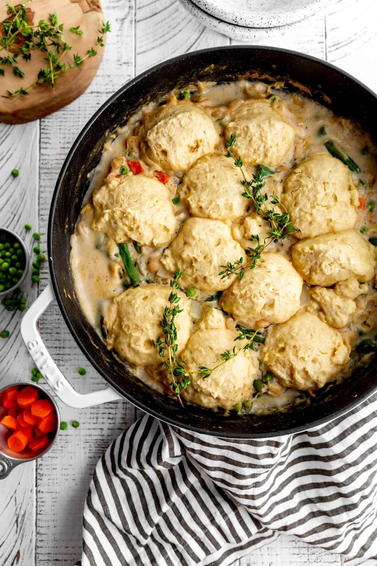 Pot of vegetable pot pie soup, a linen napkin and a cup of chopped carrots.