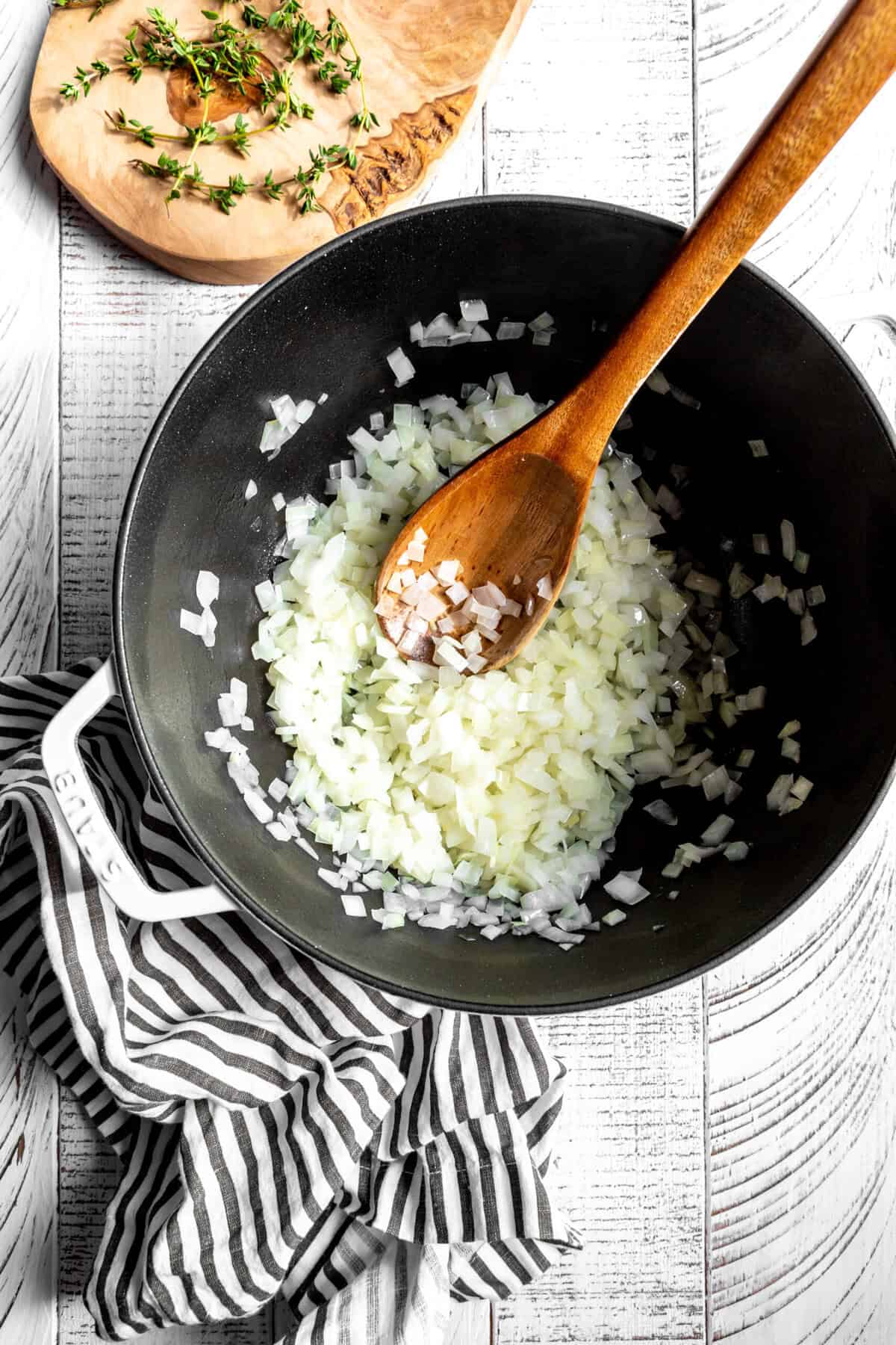 Dutch oven of sautéed onions with a wooden spoon.