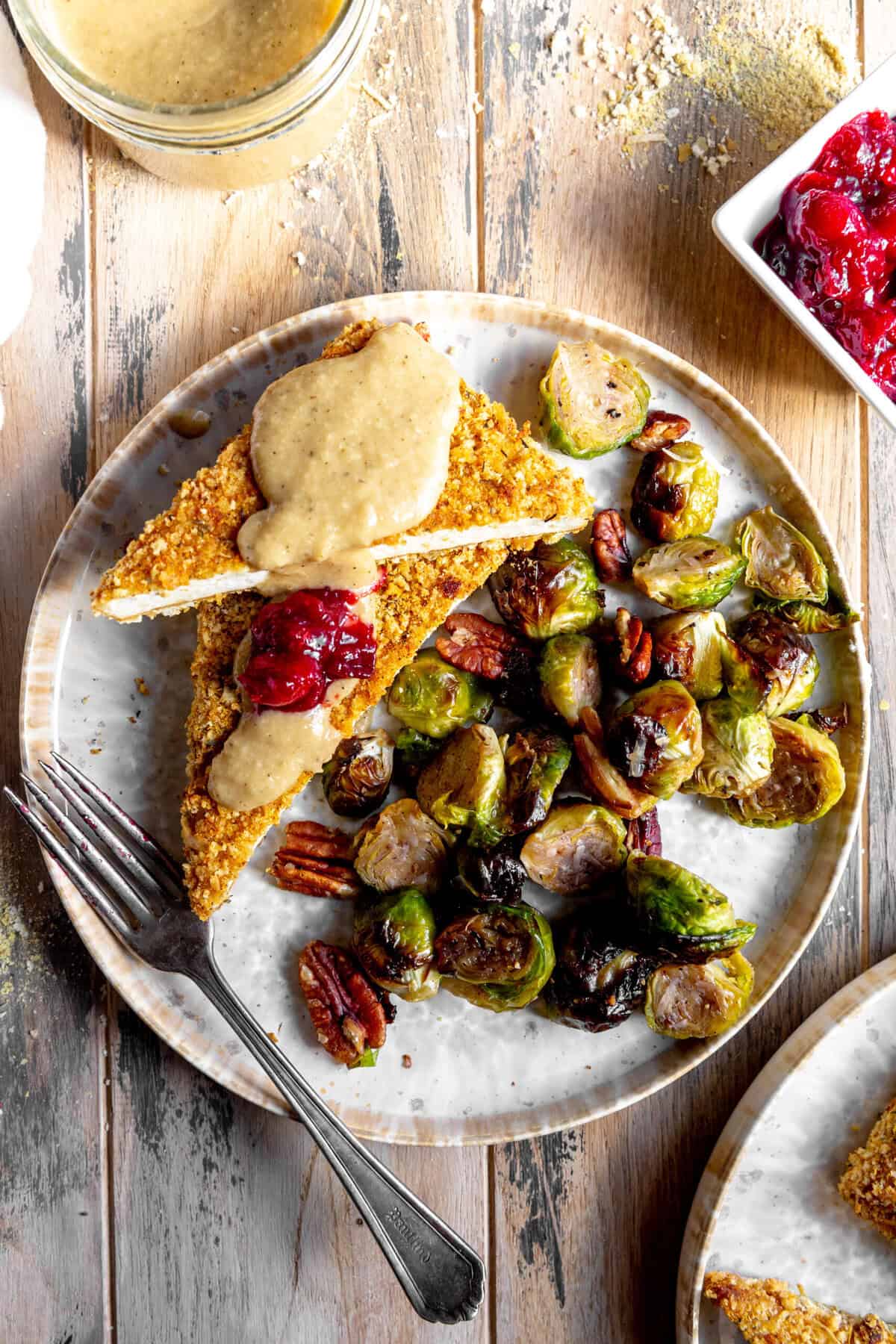Baked tofu cutlets topped with gravy and cranberry sauce.