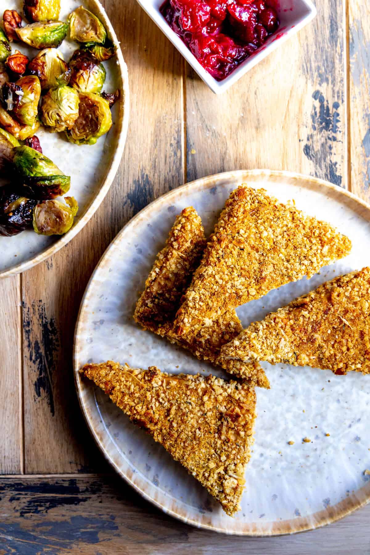 Crispy baked tofu cutlets cut into triangles on a plate.