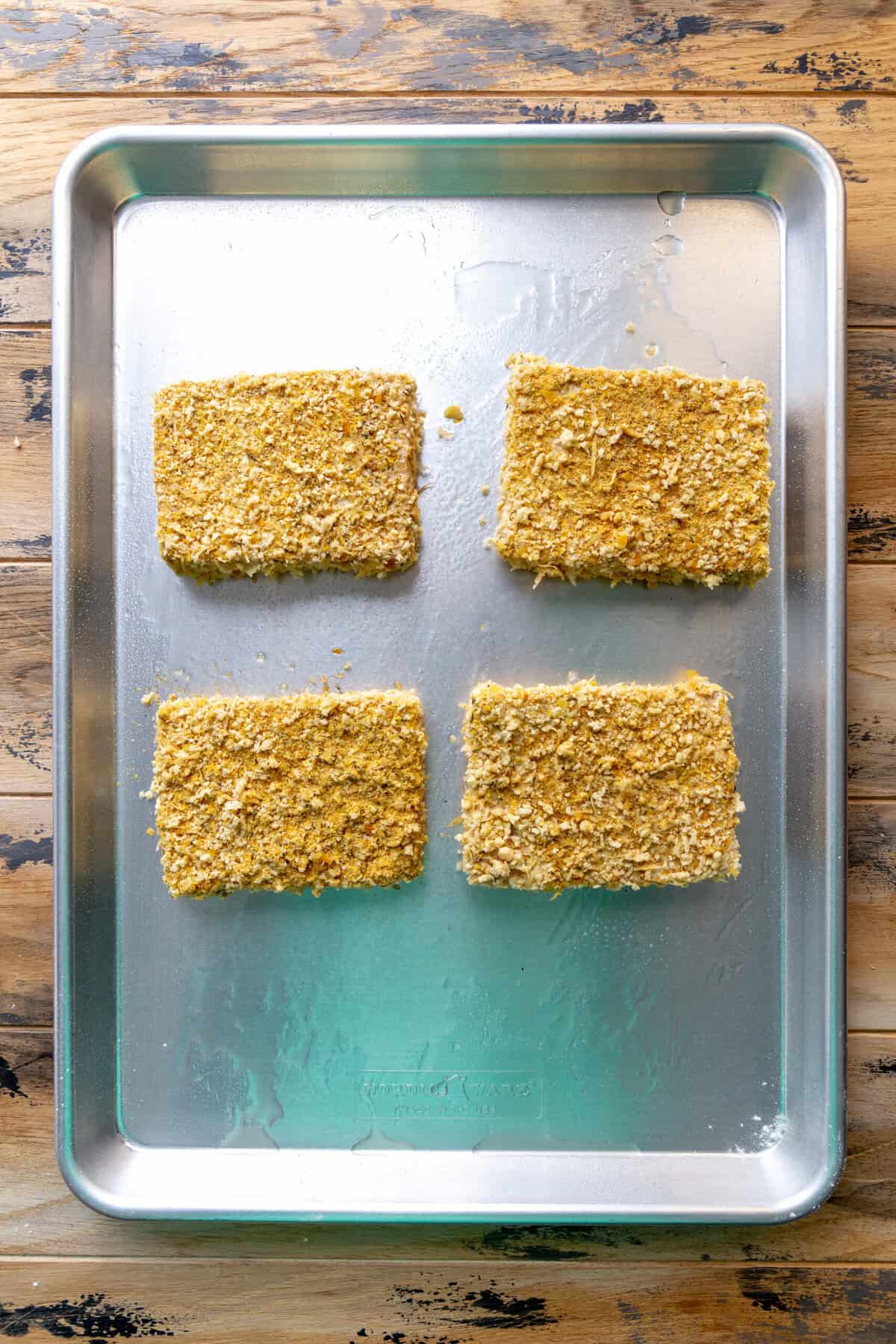Unbaked, breaded tofu cutlets on a baking sheet.
