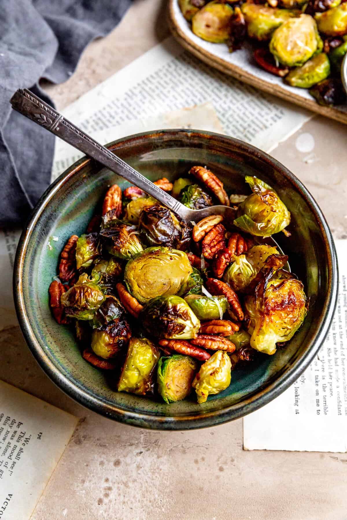 Spoon digging into a bowl of roasted brussels sprouts and pecans.