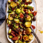 Roasted brussels sprouts on a platter with a serving spoon.