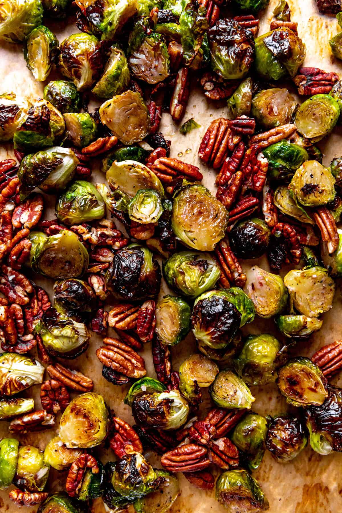 Roasted brussels sprouts and pecans on a baking sheet.