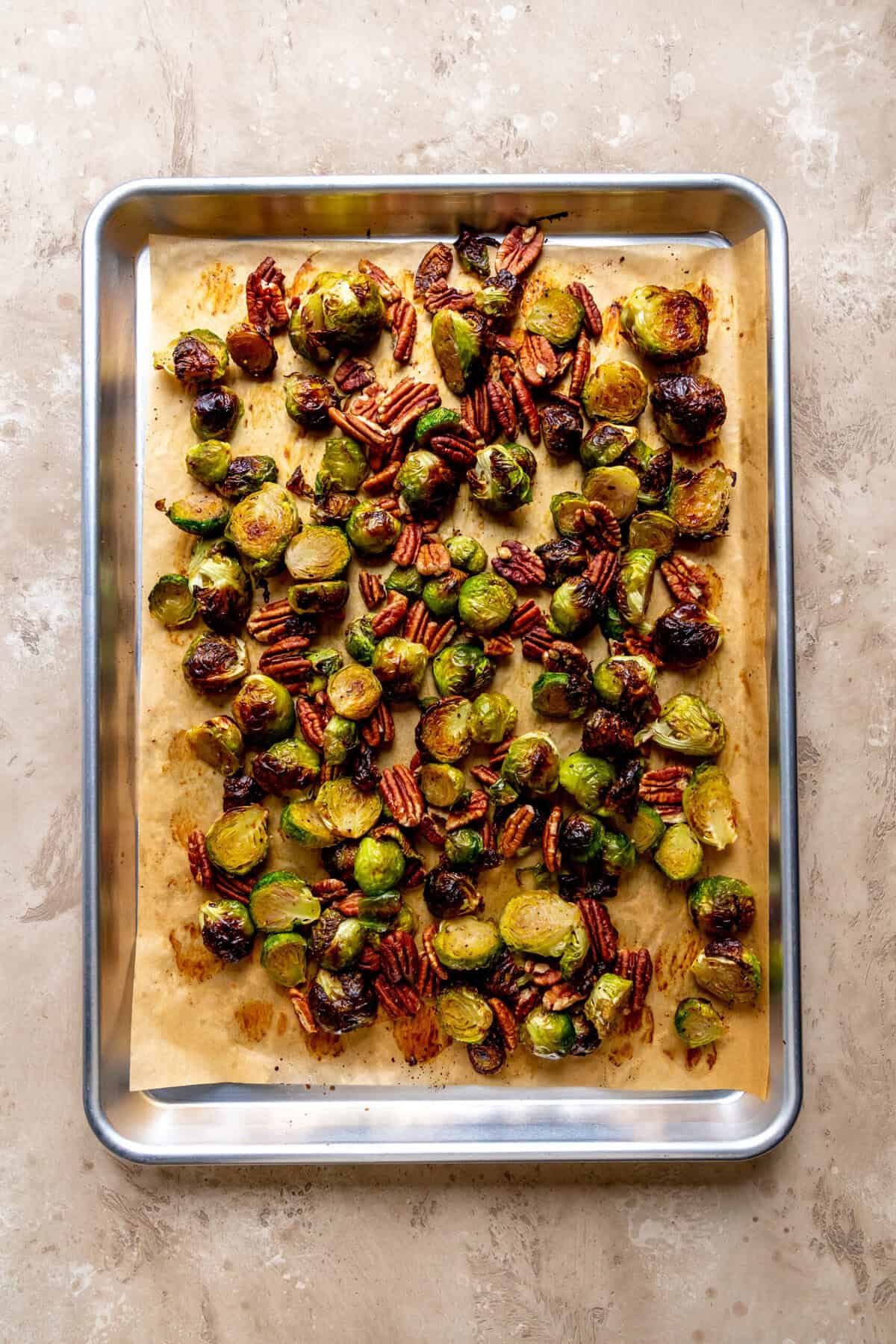 Roasted brussels sprouts and pecans on a baking sheet.