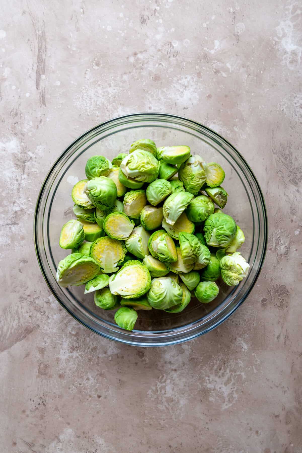 Brussels sprout halves in a glass bowl.