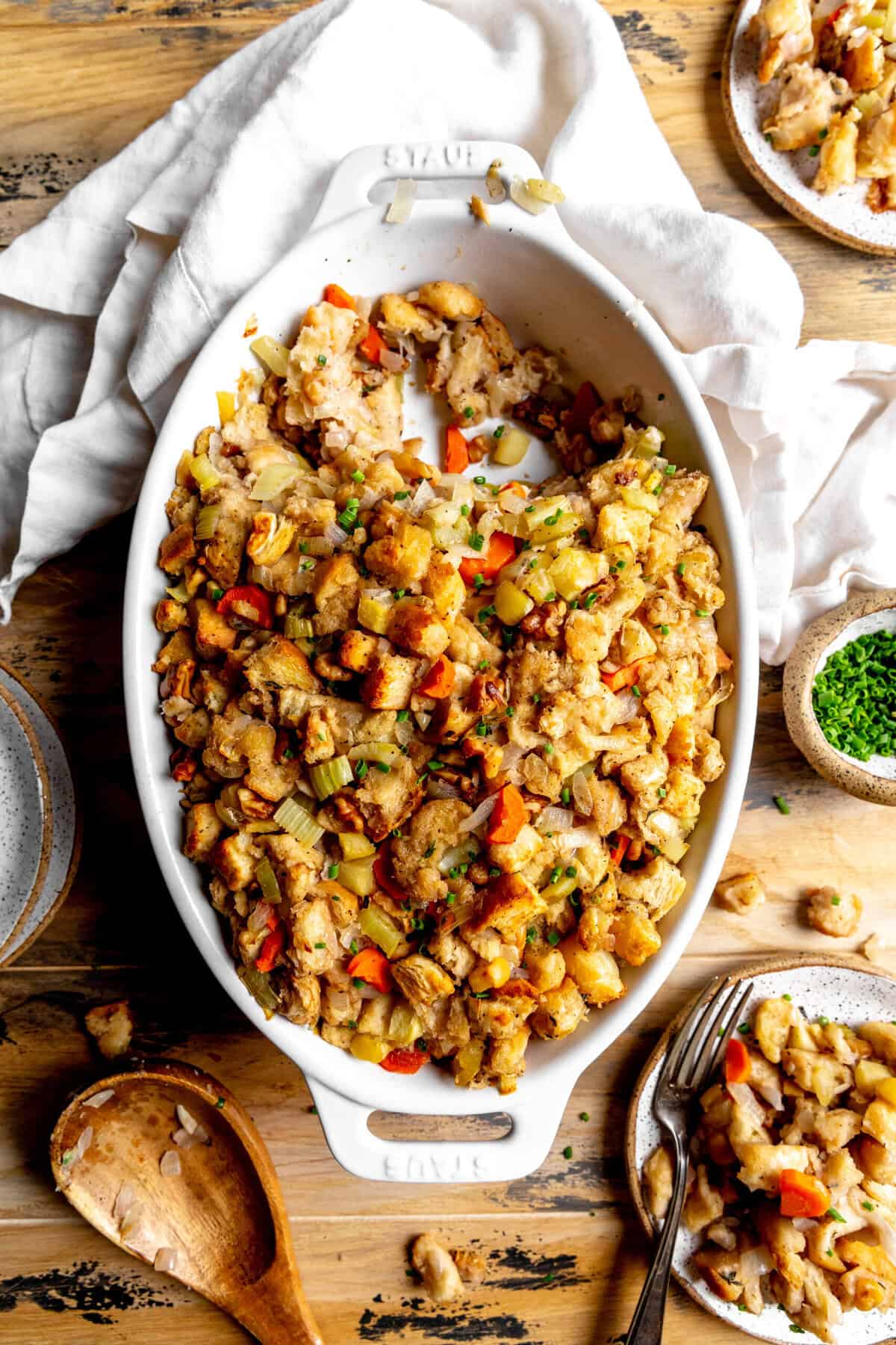 Casserole dish of vegan stuffing and two small plates of stuffing.