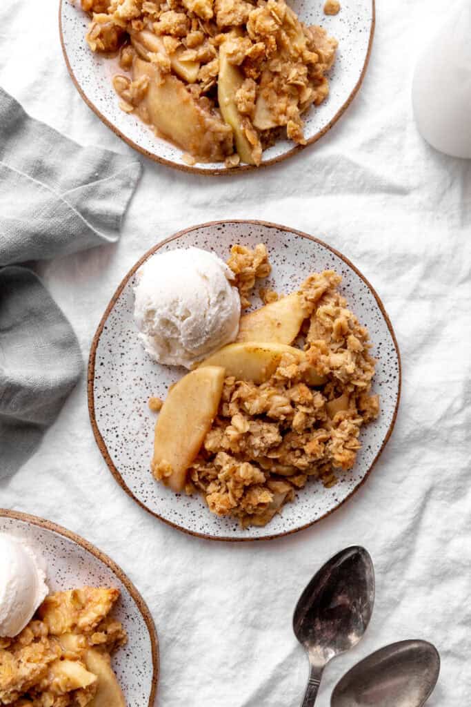 Three plates of apple crisp and ice cream and a glass of milk.