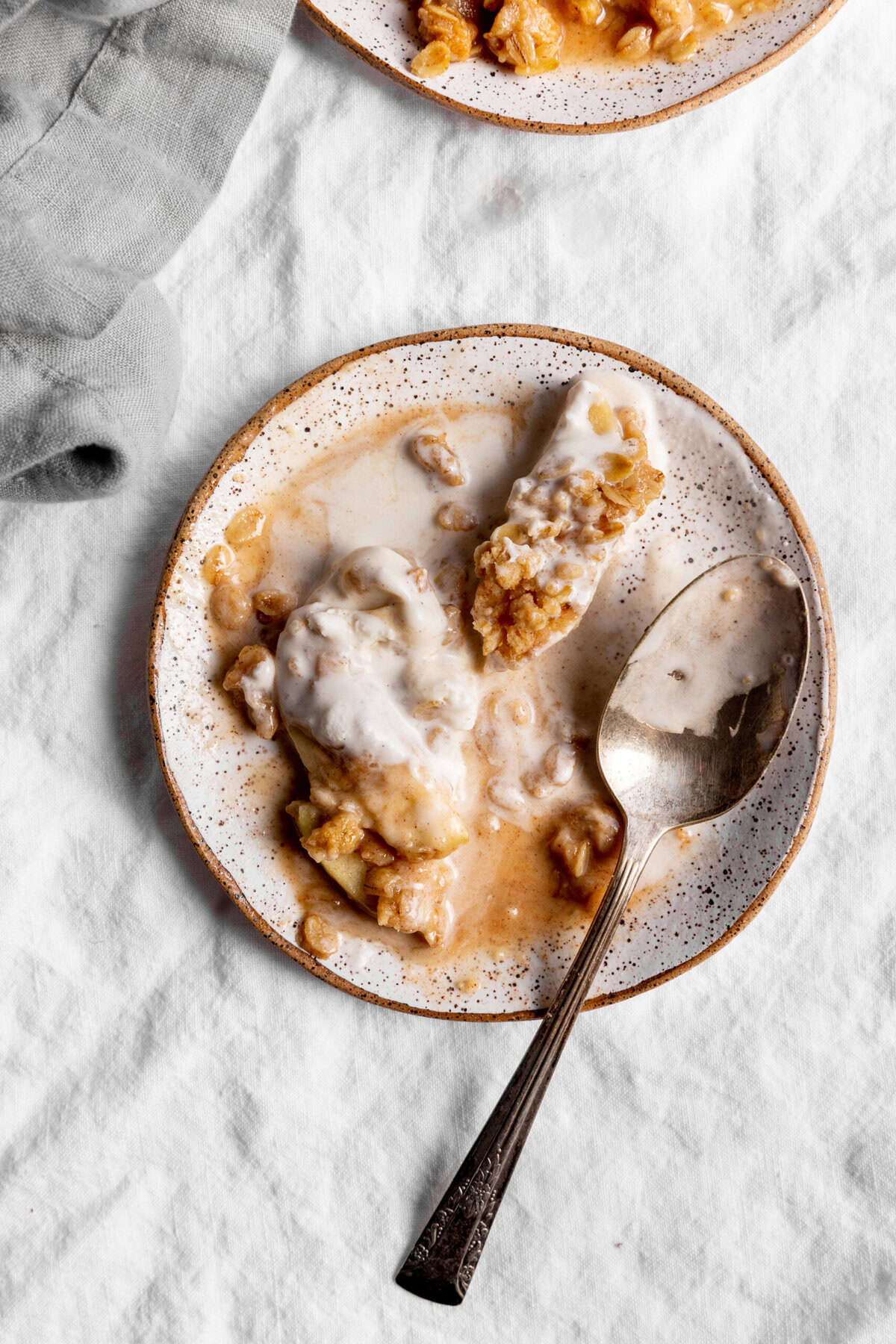White plate with melted ice cream and an apple slice with a spoon.