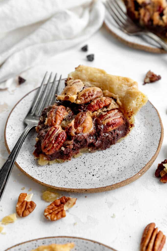 Slice of chocolate bourbon pecan pie on a white plate with a fork.