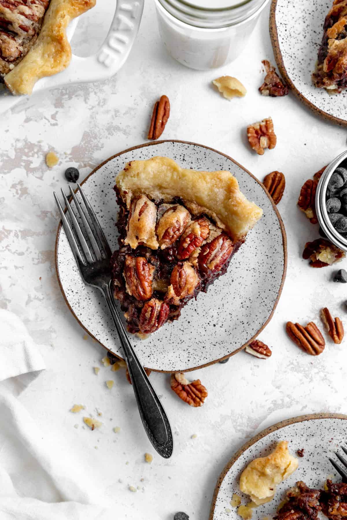 Plates with slices of chocolate bourbon pecan pie and a cup of milk.