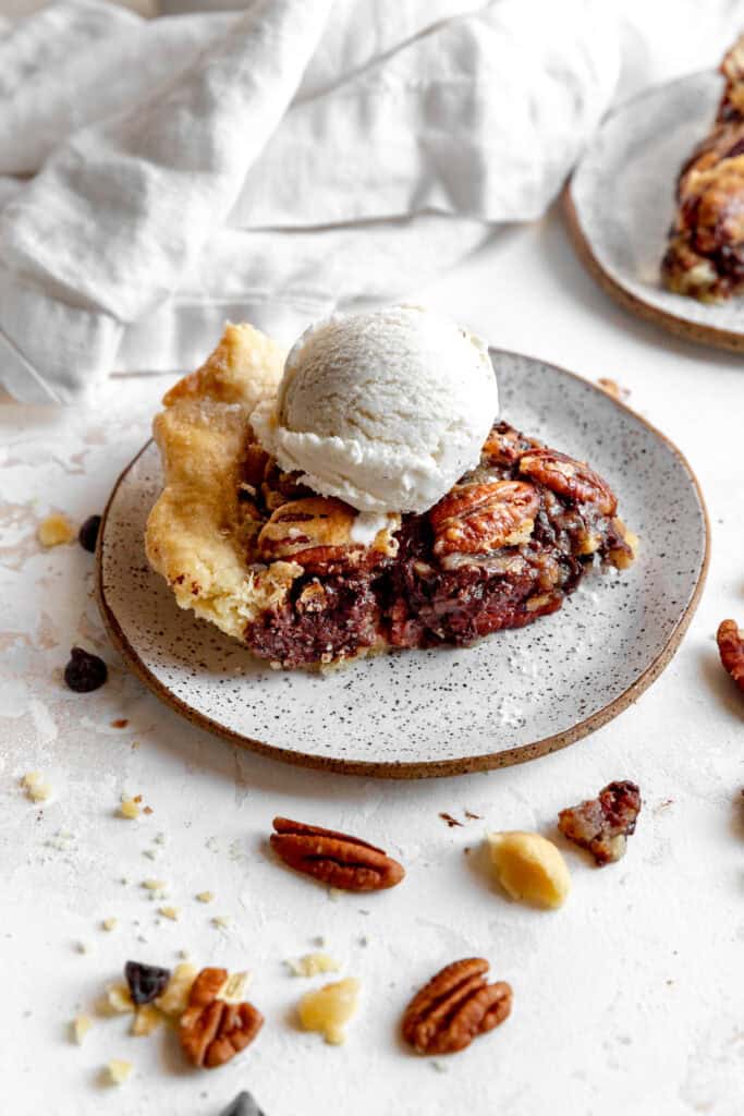 Slice of chocolate bourbon pecan pie topped with a scoop of vanilla ice cream.