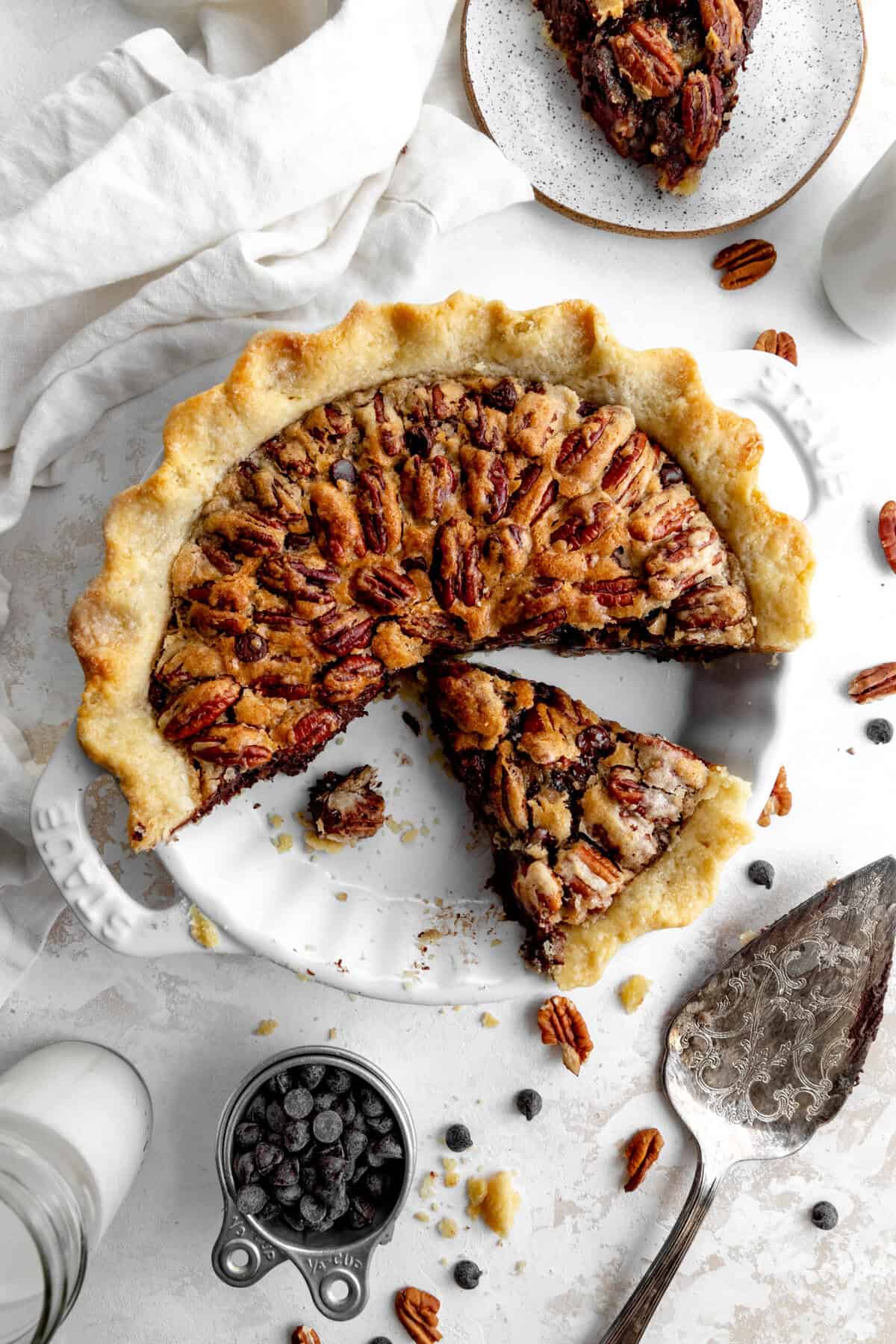 Chocolate pecan pie, a linen napkin and a cup of chocolate chips.