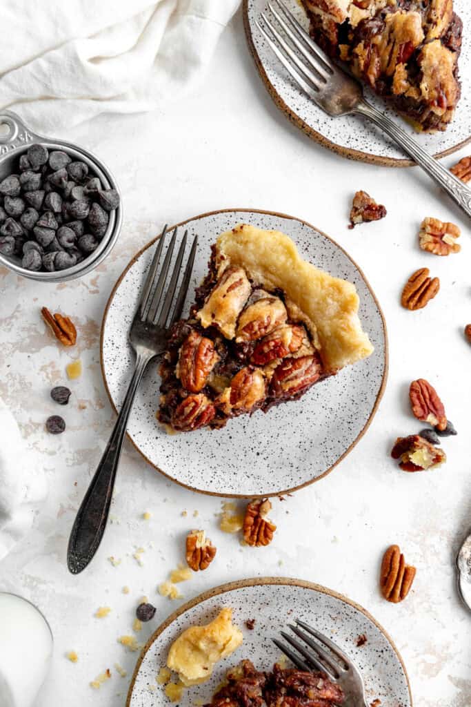 Slice of chocolate bourbon pecan pie on a white plate with a fork.