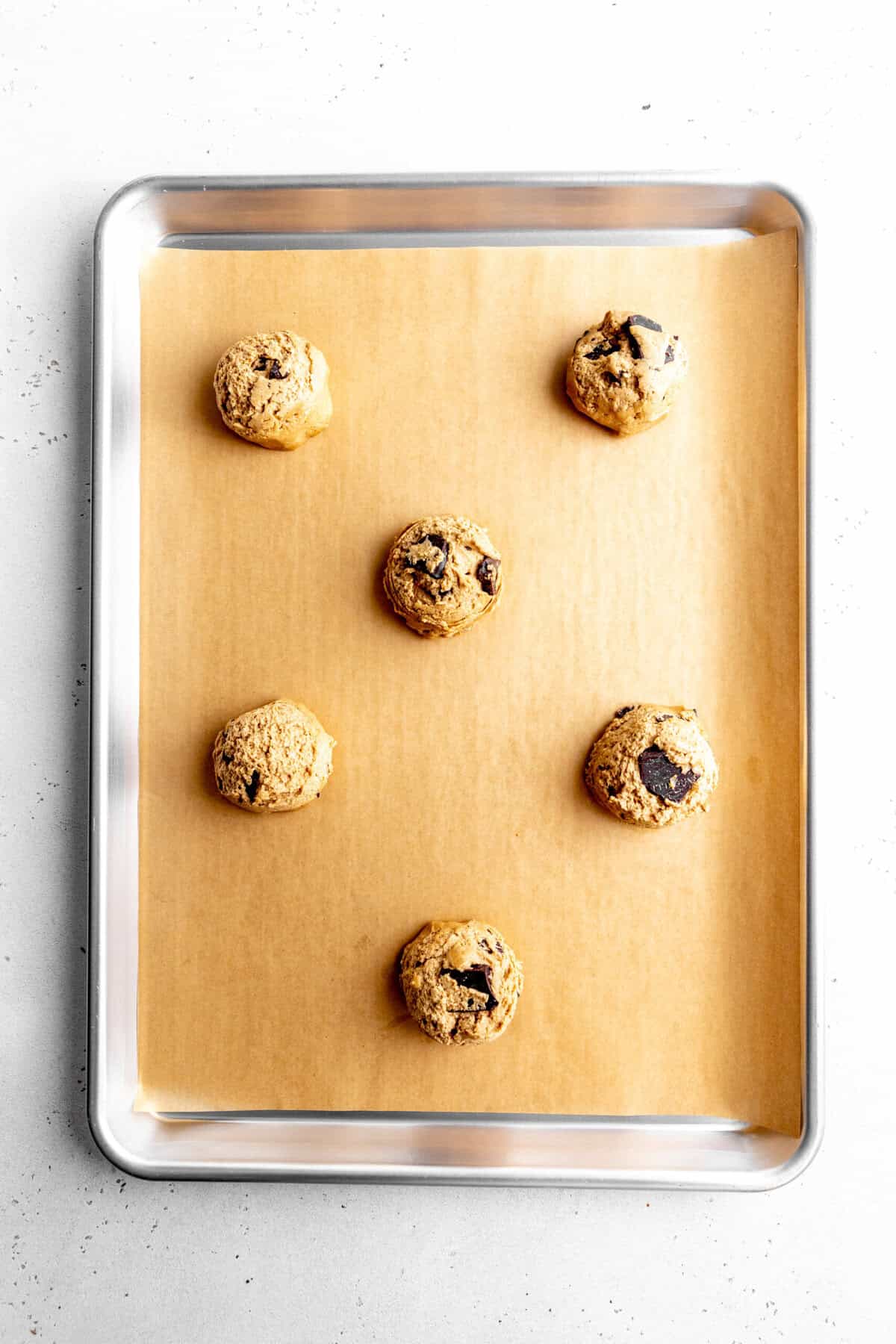 Unbaked espresso chocolate chip cookies on a baking sheet.
