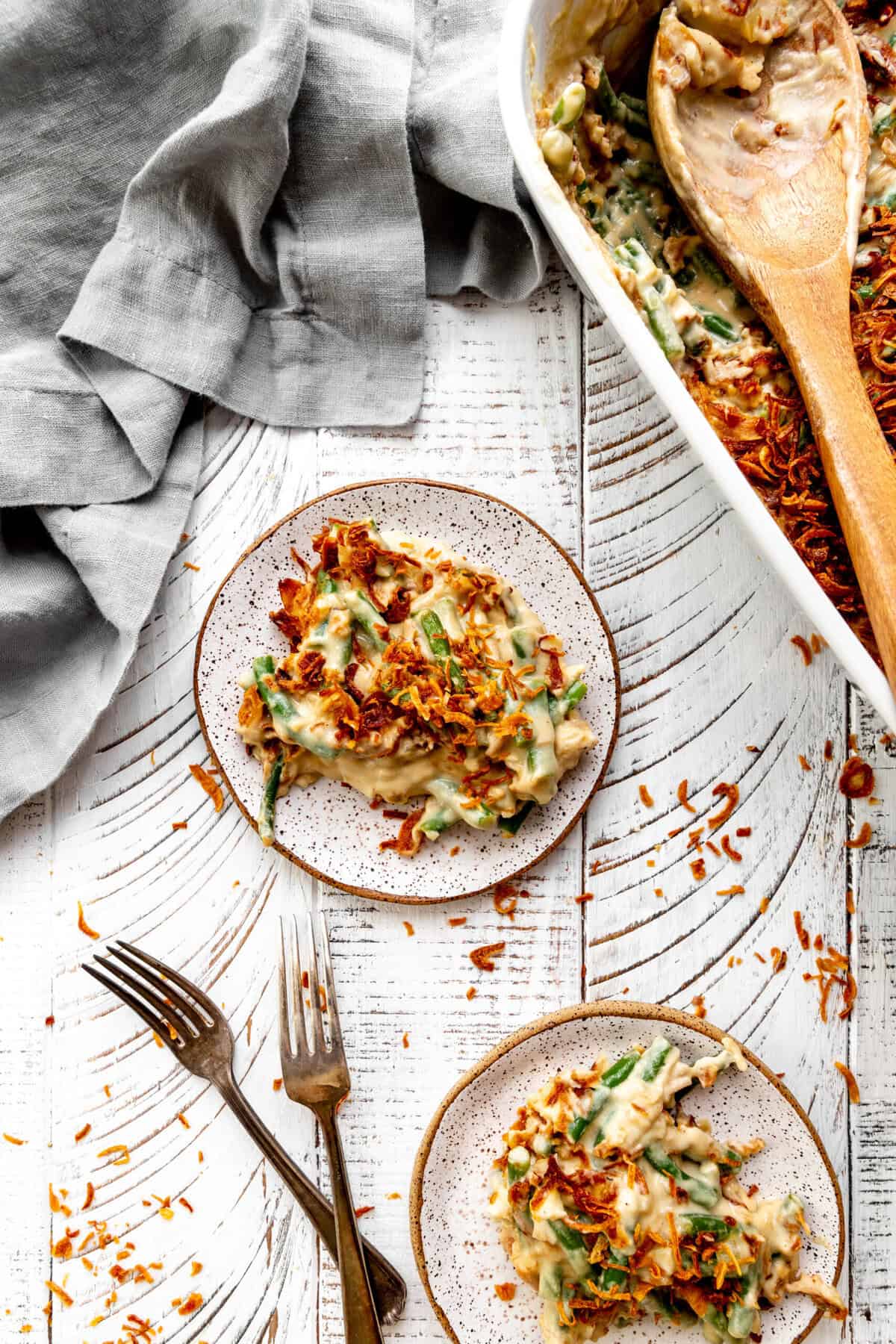 Two small plates of green bean casserole and two forks.