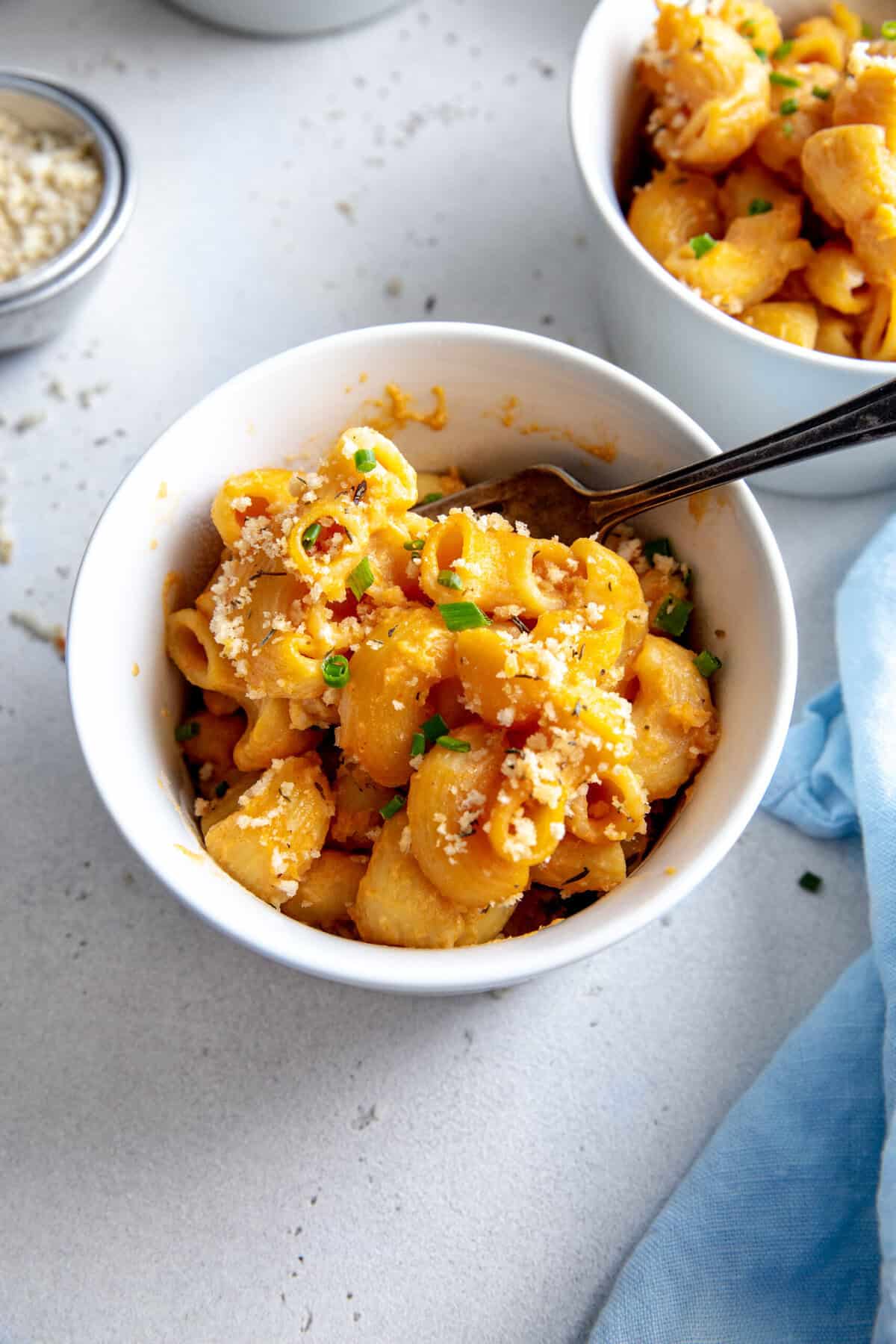 Fork digging into a bowl of mac and cheese.