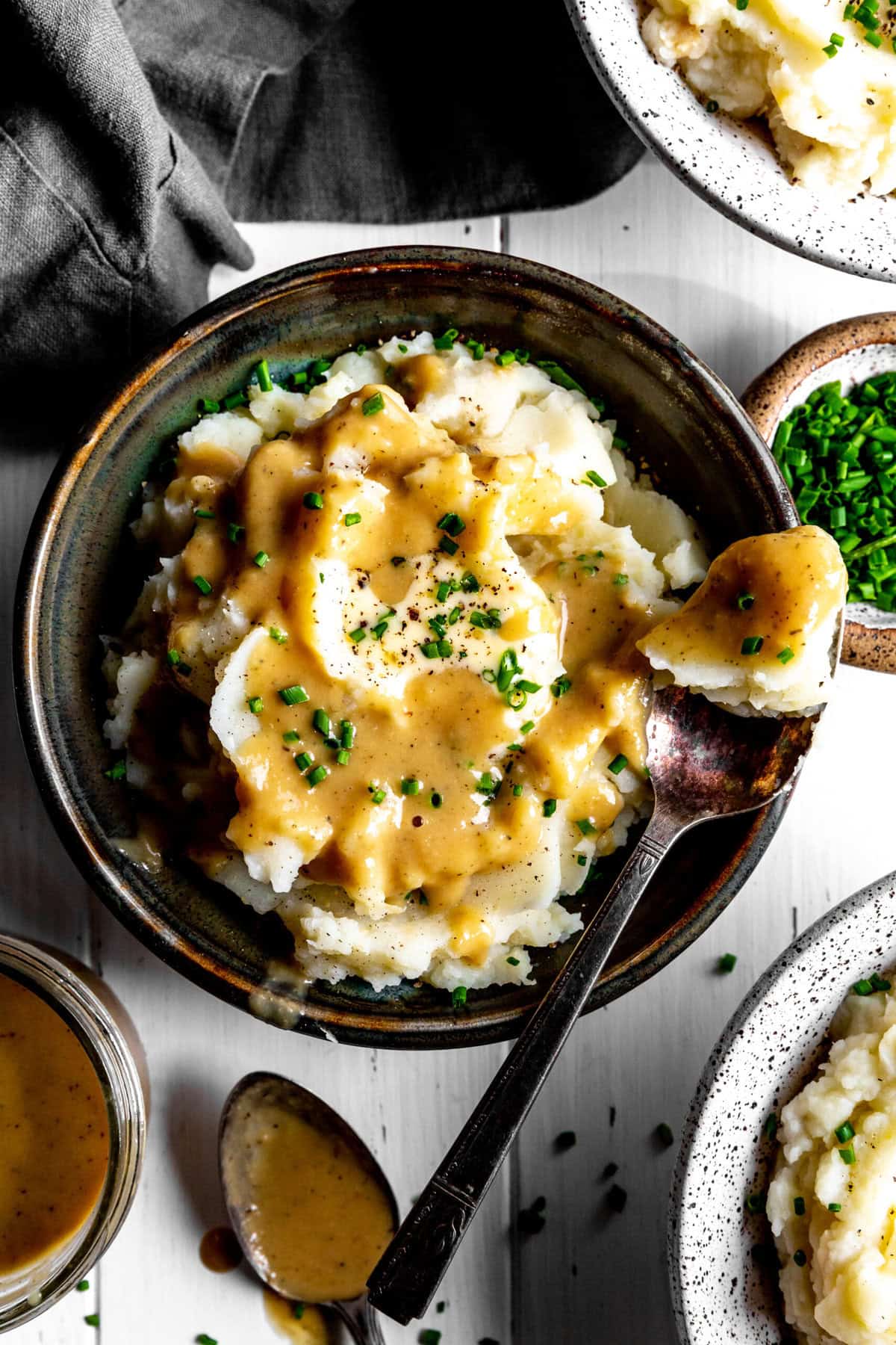 Spoonful of mashed potatoes and gravy and a cup of fresh chives.