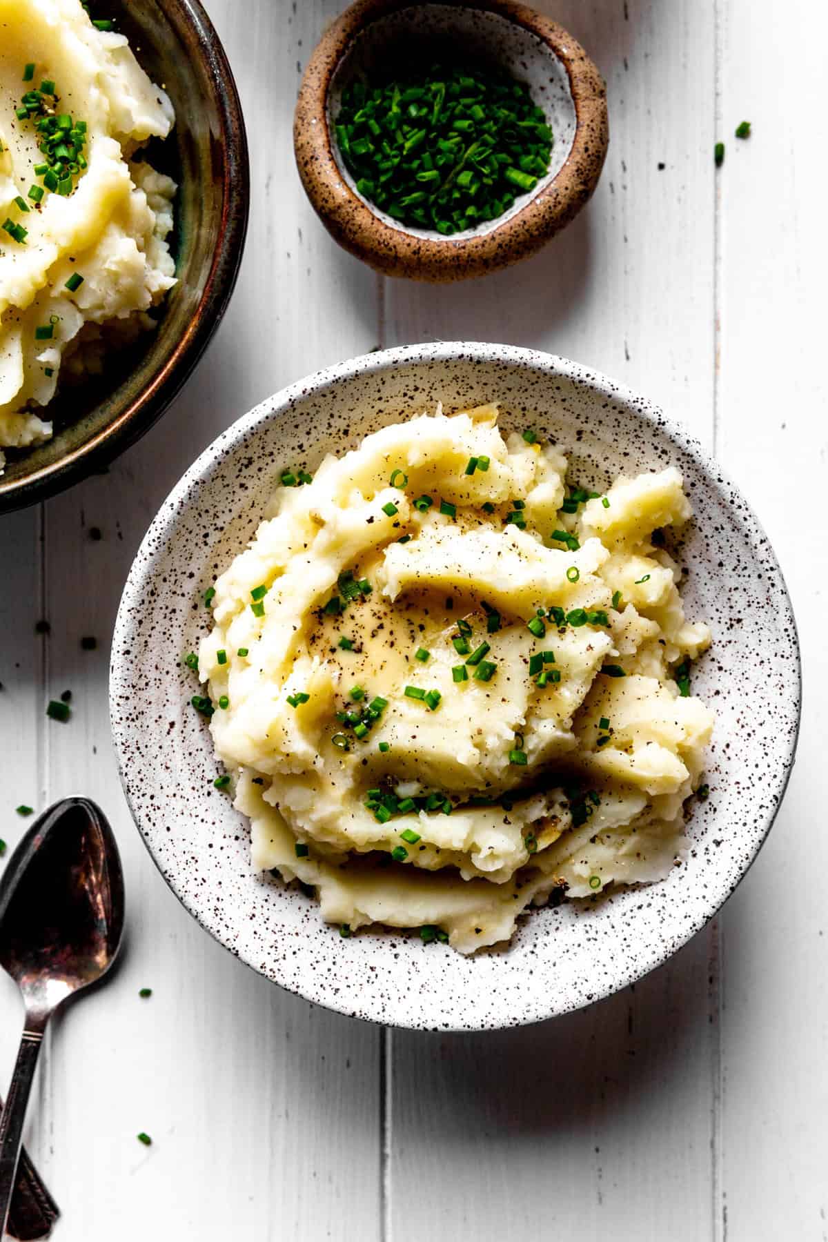 Bowl of mashed potatoes and a small bowl of fresh chives.