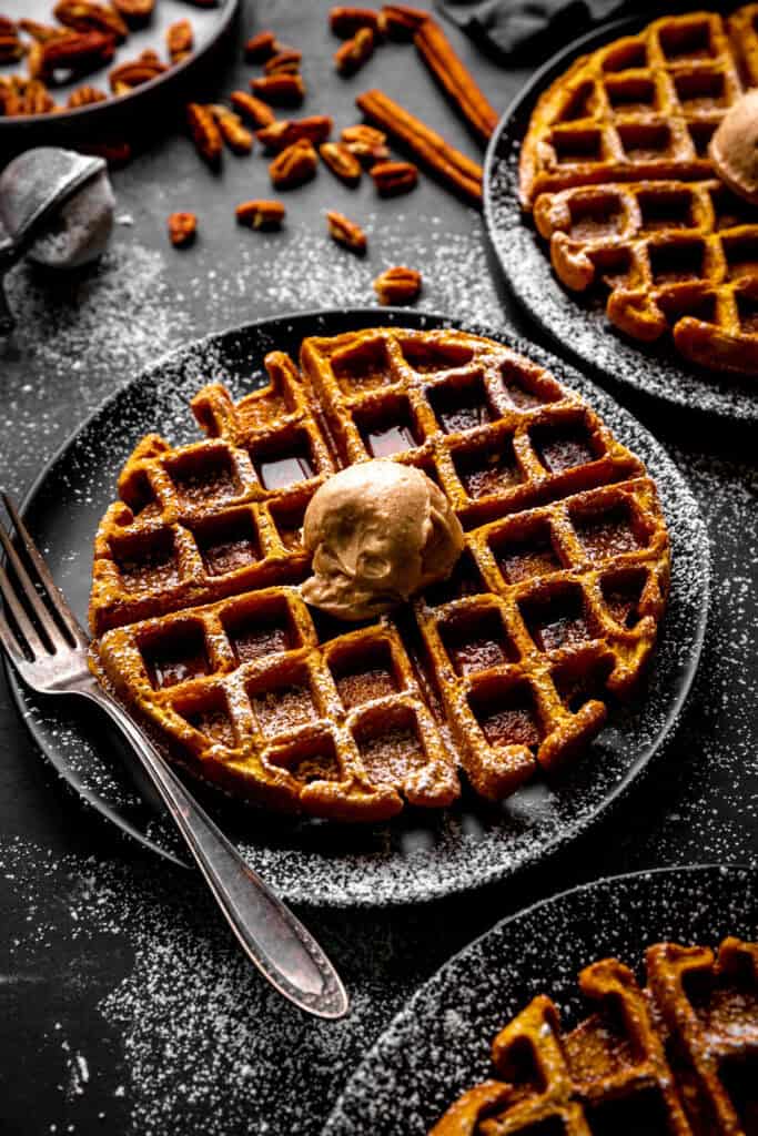 Pumpkin waffle on a black plate with a fork.