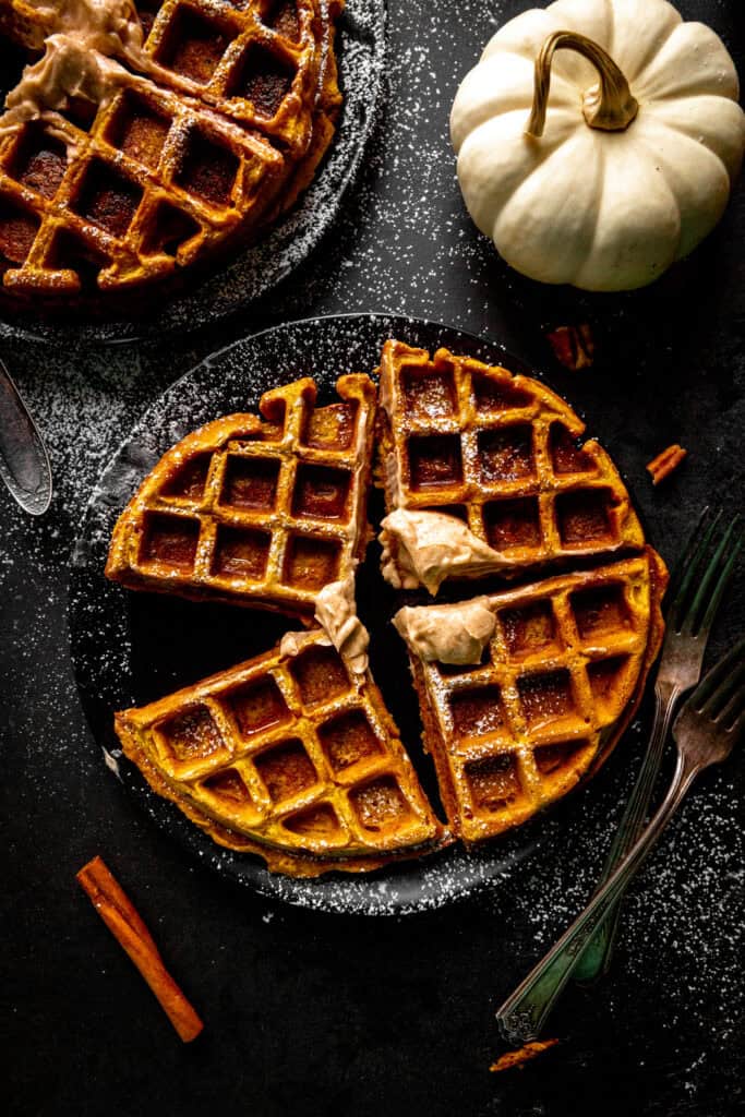 Four pumpkin waffle sections on a plate and a white pumpkin.