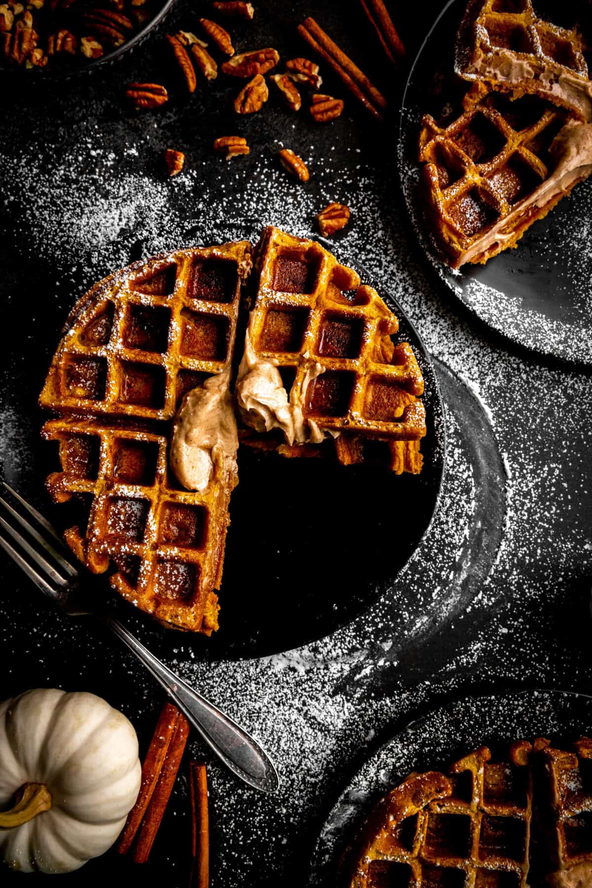 Pumpkin waffle with a section missing and smeared cinnamon butter.